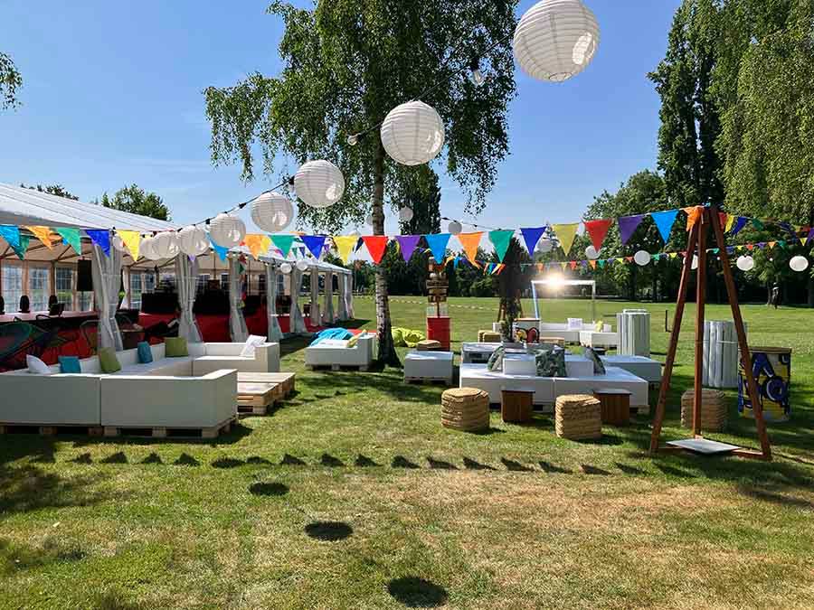 Outdoor event area with plenty of seating, decorated with bright colours, lanterns and bunting, creating a playful atmosphere.