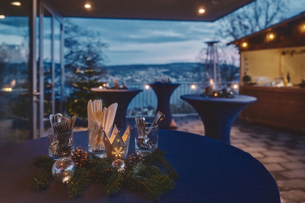 A winter patio decoration with tables decorated with pine cones, candles and snowflakes.